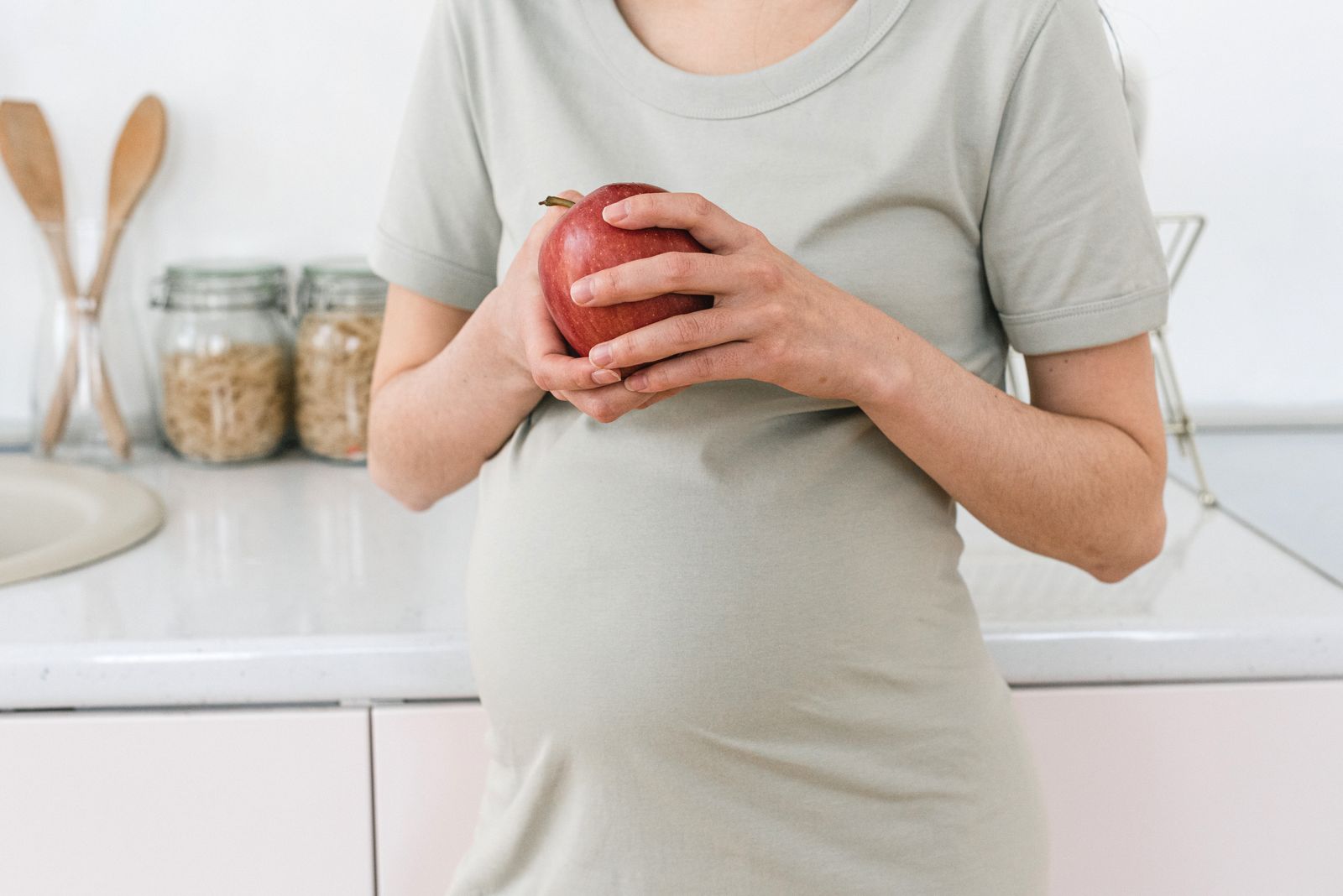 Pregnant person holding a red apple