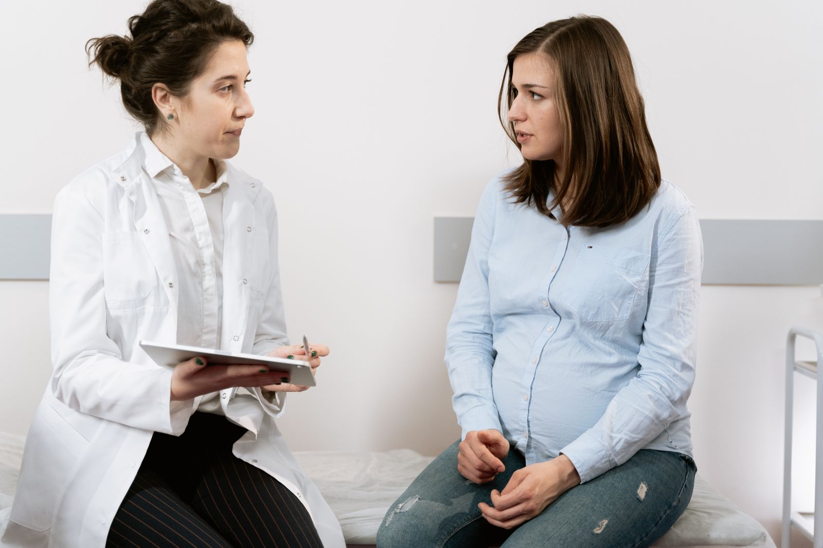 Pregnant person consulting with a clinician using a tablet