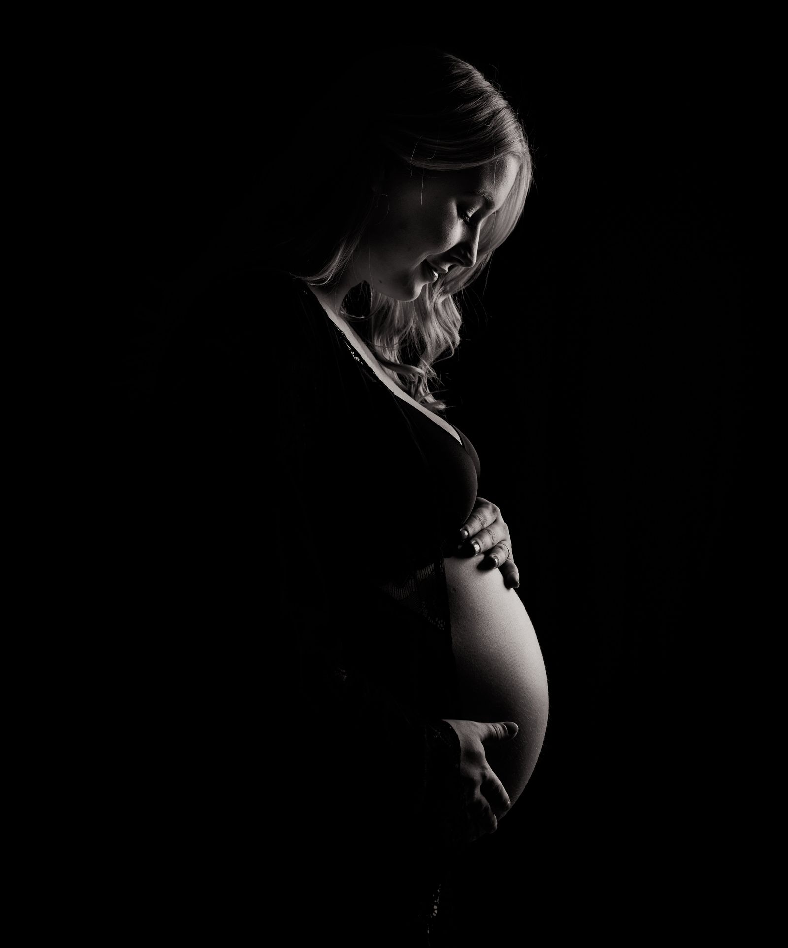 Pregnant person standing in a cardigan for a calm maternity portrait