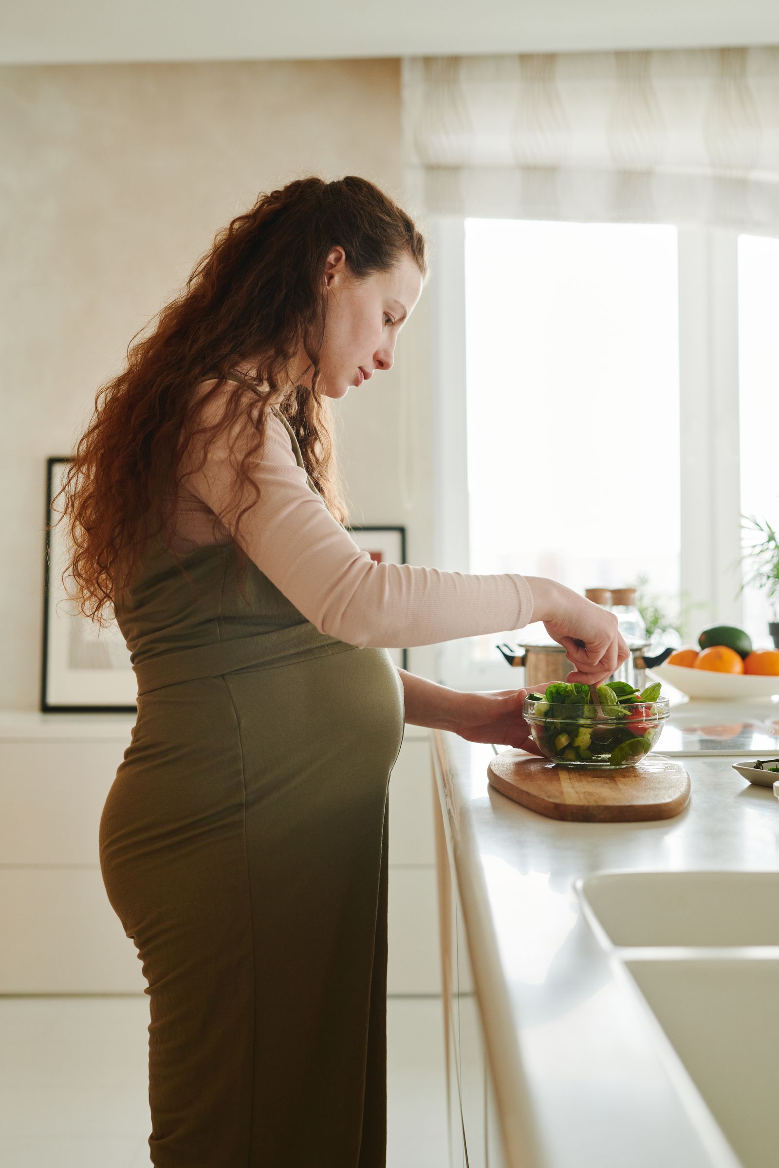 Pregnant person preparing a vegetable salad