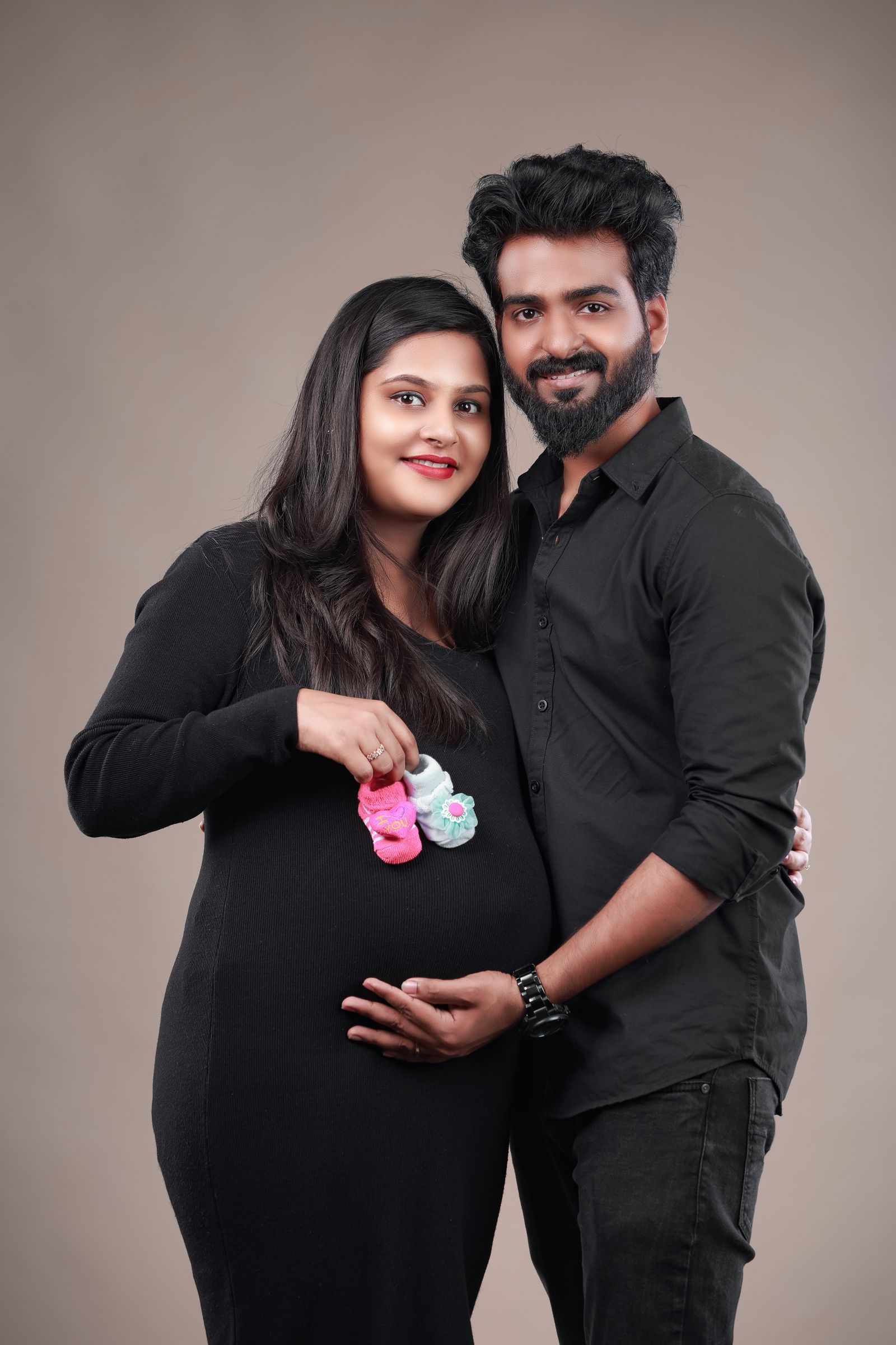 Expecting couple holding tiny shoes