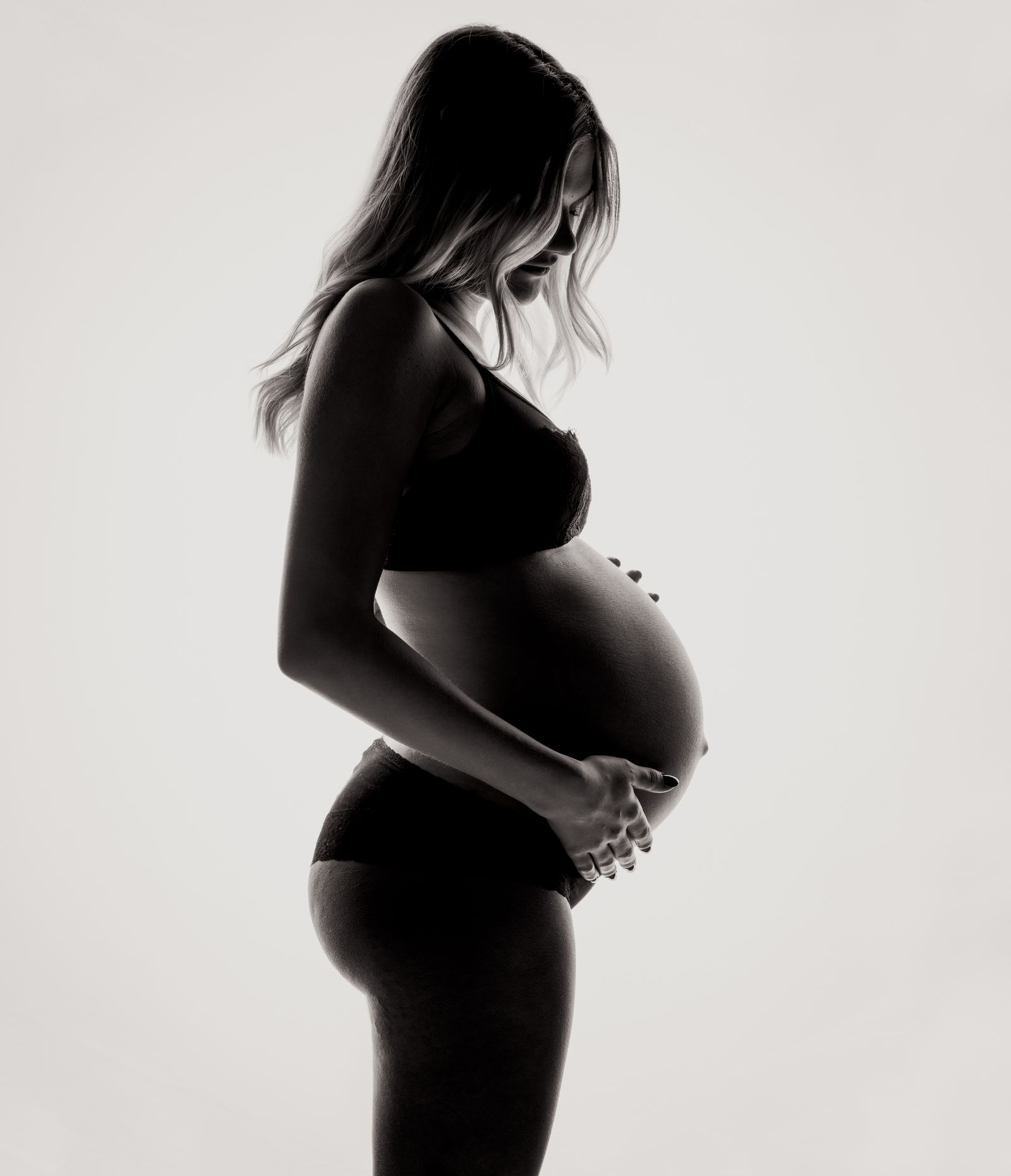 Pregnant person seated indoors with hands near their belly